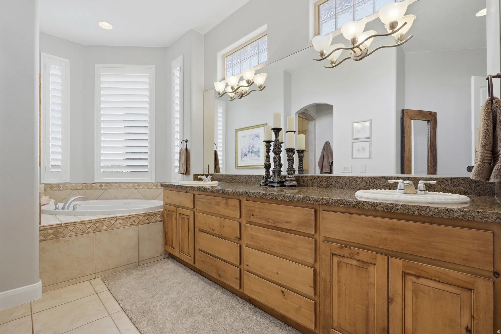 Dual vanity with wood cabinetry, granite-style countertop, and integrated sinks