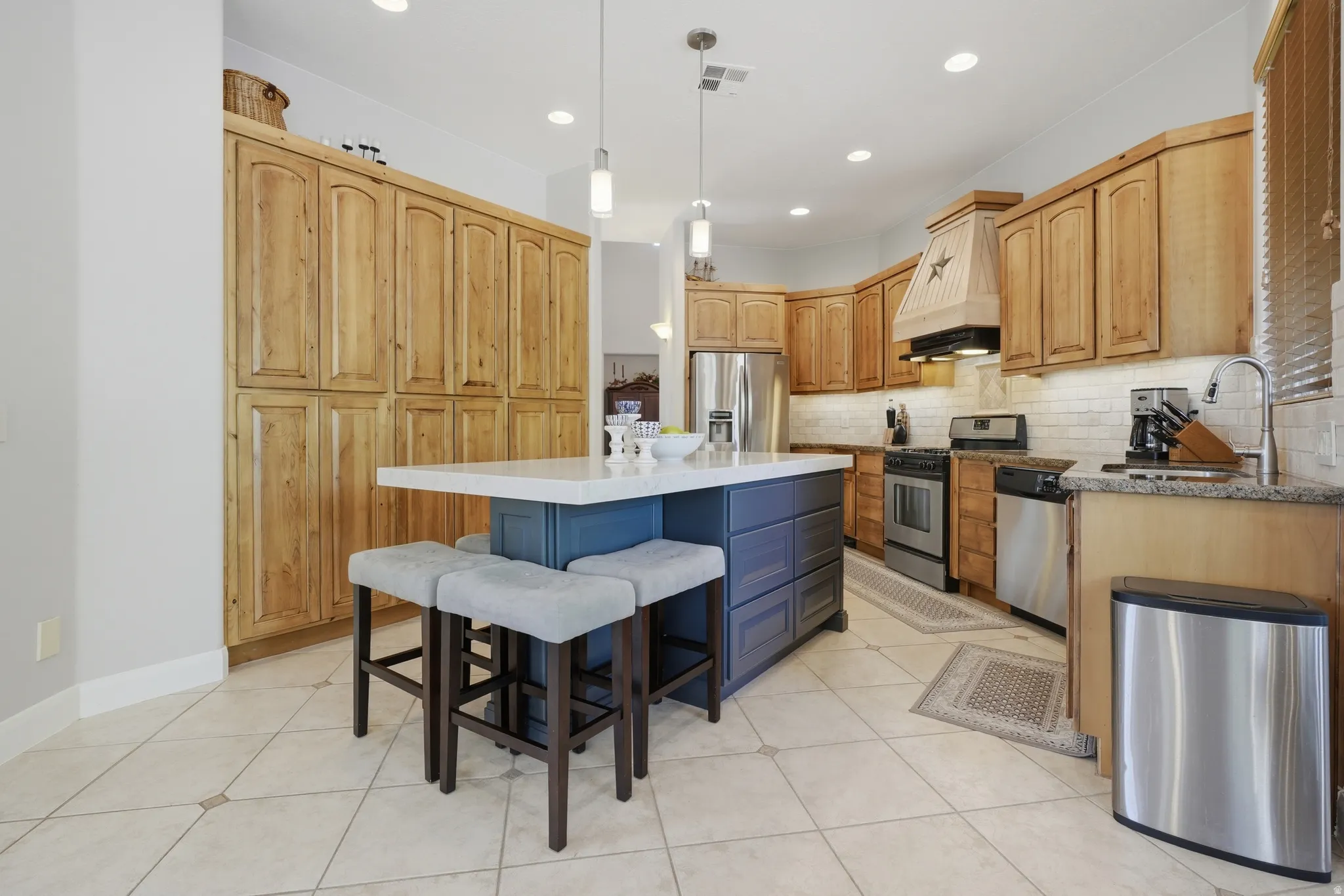 Spacious kitchen featuring a central island with countertop seating, stainless steel appliances, extensive cabinetry, and tile flooring