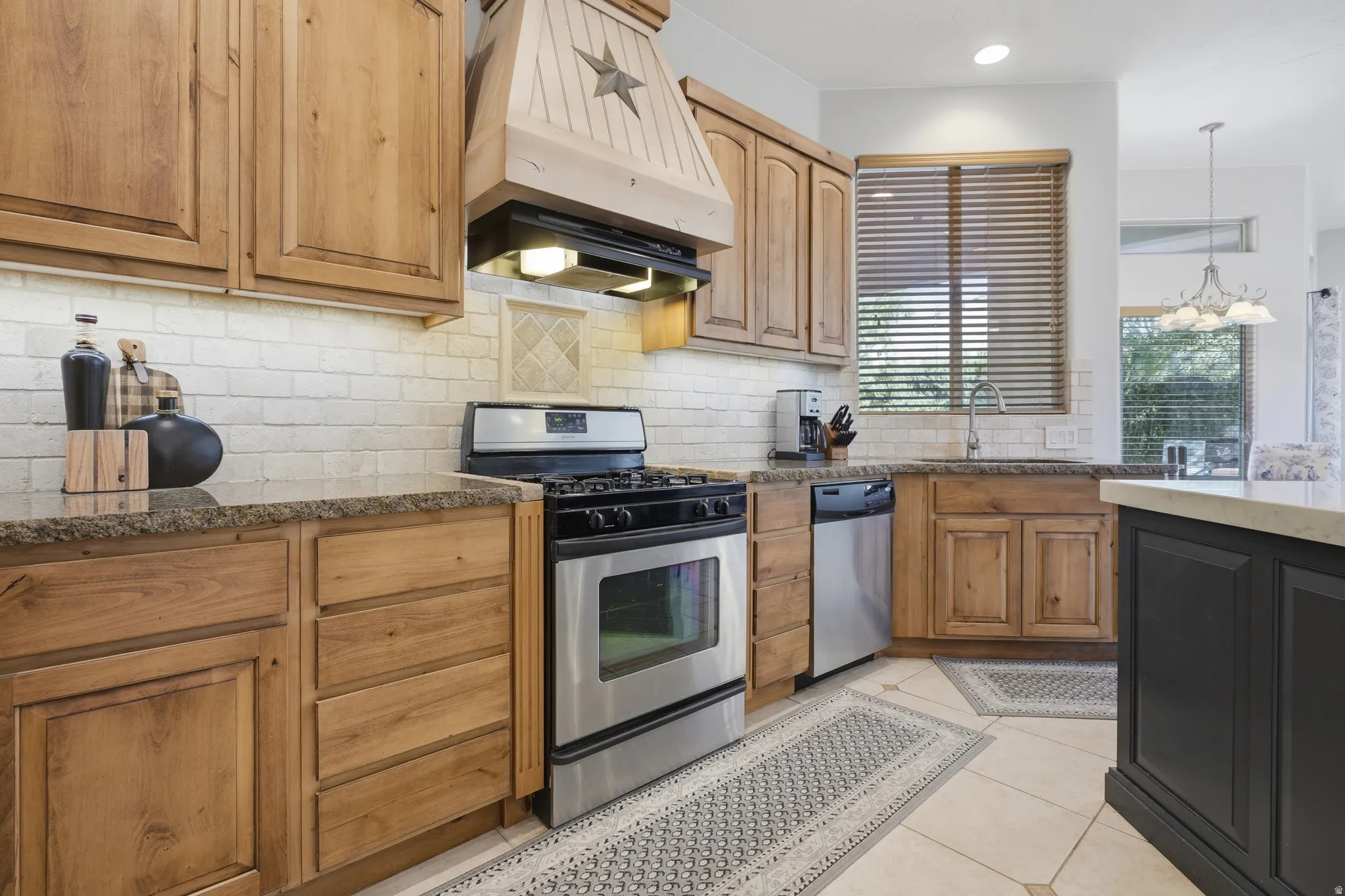Kitchen featuring wood cabinetry, a decorative range hood, stainless steel appliances, and a tiled backsplash