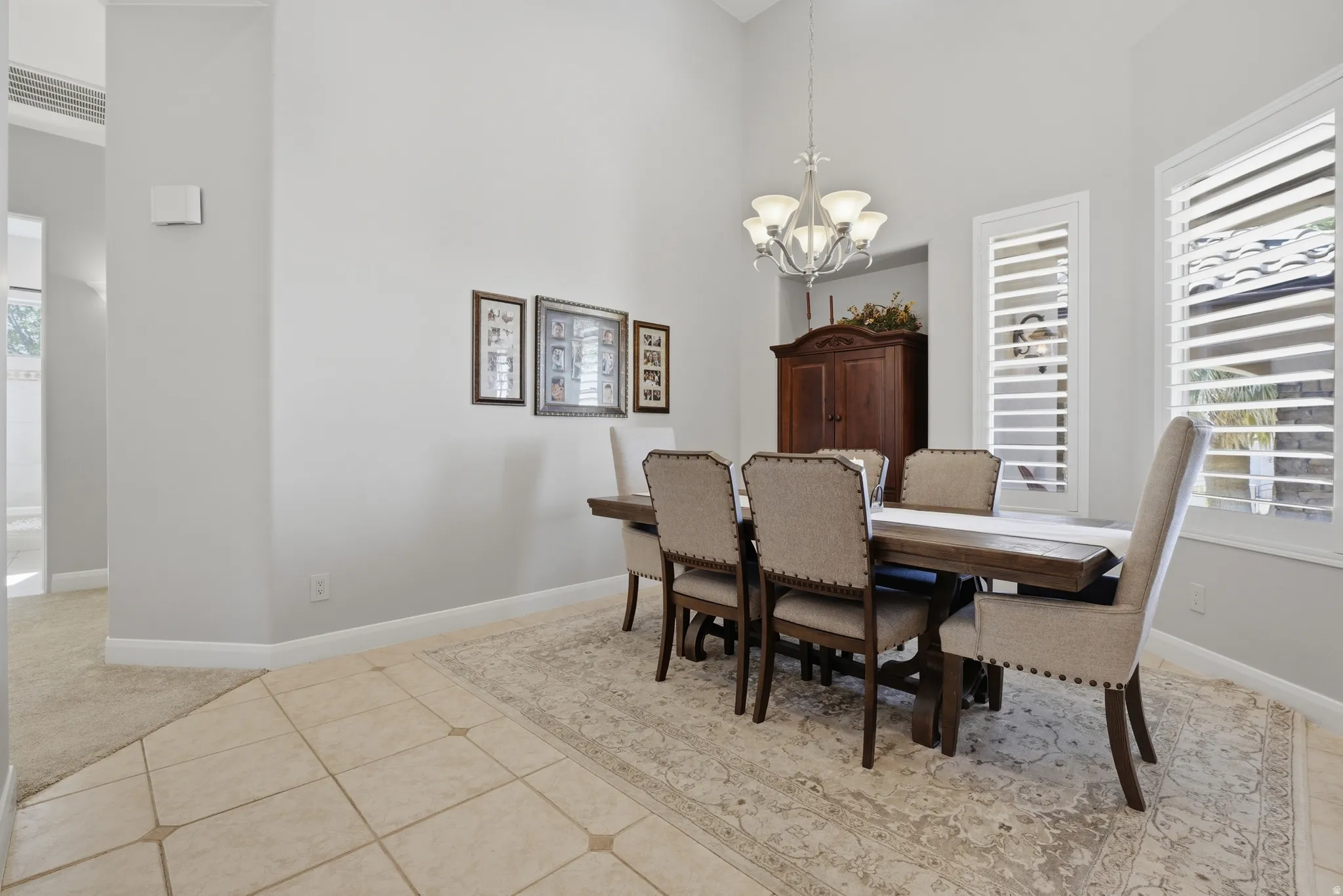 Spacious interior featuring a vaulted ceiling, tile flooring, and plantation shutters