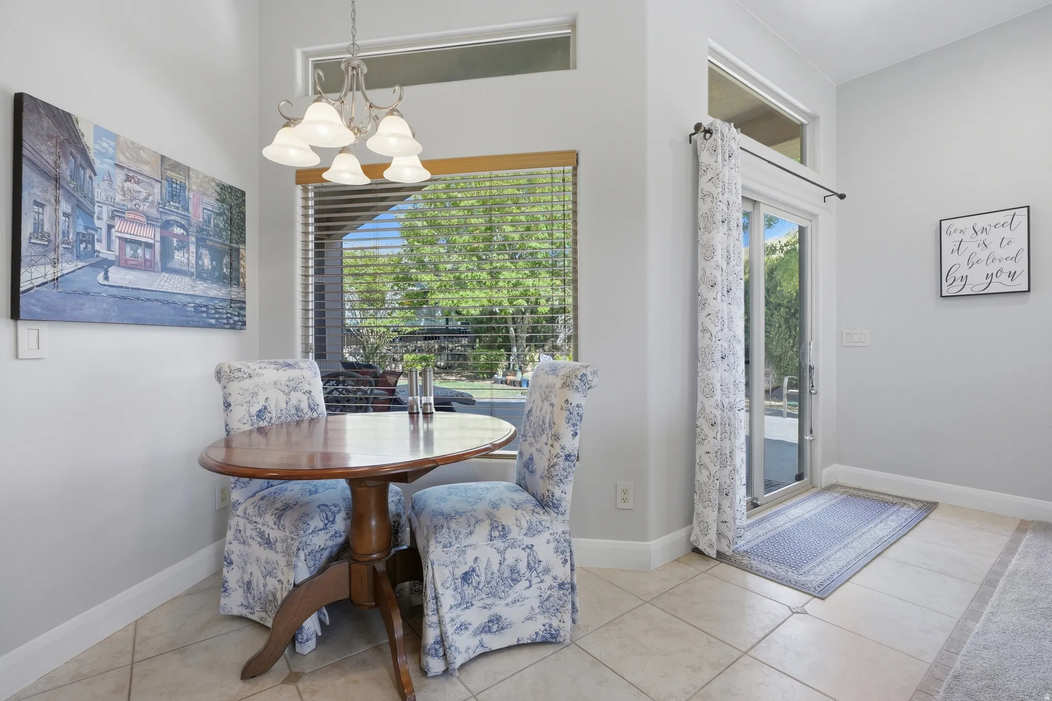 Dining area featuring tile flooring, a large window with horizontal blinds, and a sliding glass door providing exterior access