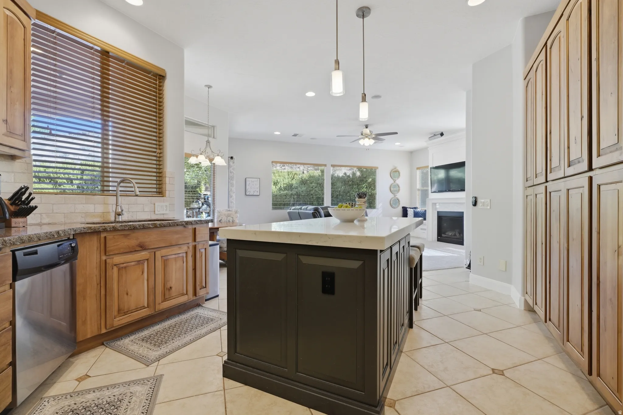 Kitchen featuring a central island with countertop, stainless steel dishwasher, tile flooring, and light-toned cabinetry