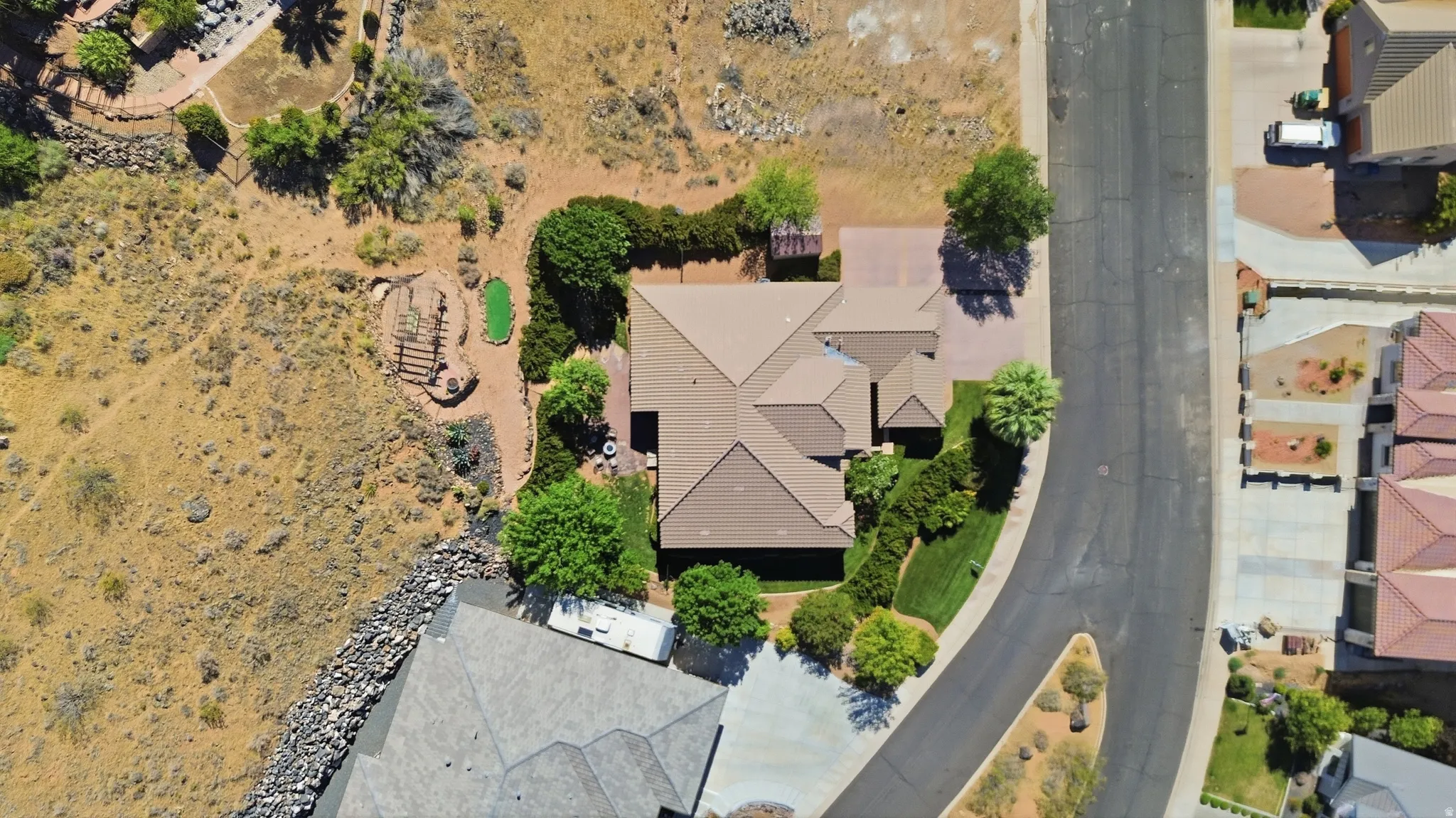 Aerial view showcasing a property with a multi-gabled roofline, a manicured lawn, and mature trees