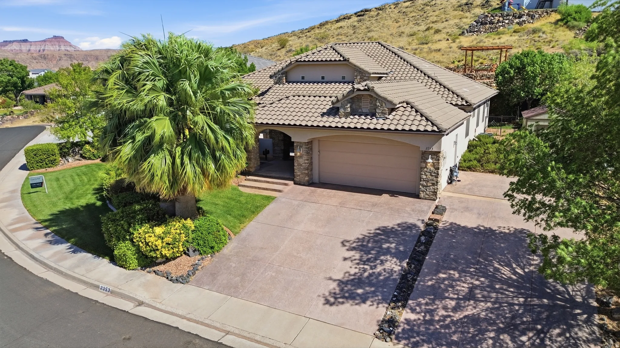 Mediterranean-style residence featuring a tile roof, an integrated two-car garage, and a textured driveway