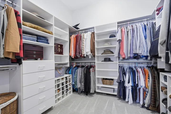Custom closet system featuring multiple hanging rods, integrated shelving, built-in drawers, and dedicated shoe storage