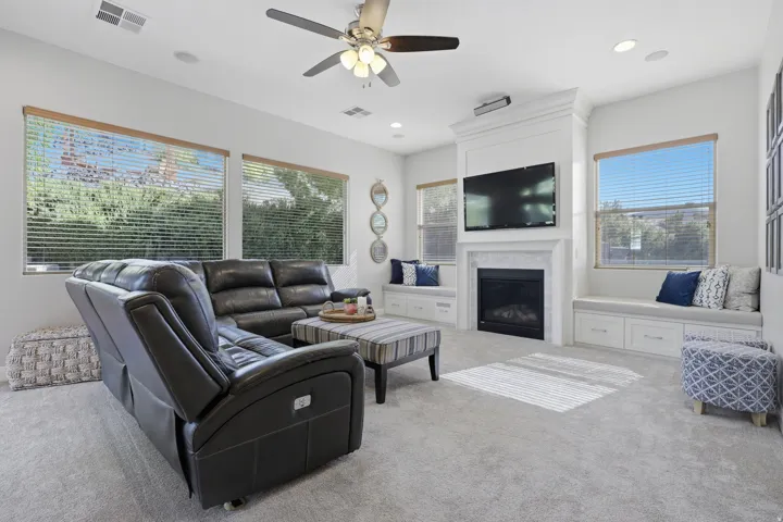Spacious living area featuring a built-in fireplace with a white mantel, recessed lighting, and a ceiling fan