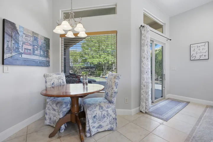 Dining area featuring tile flooring, a large window with horizontal blinds, and a sliding glass door providing exterior access