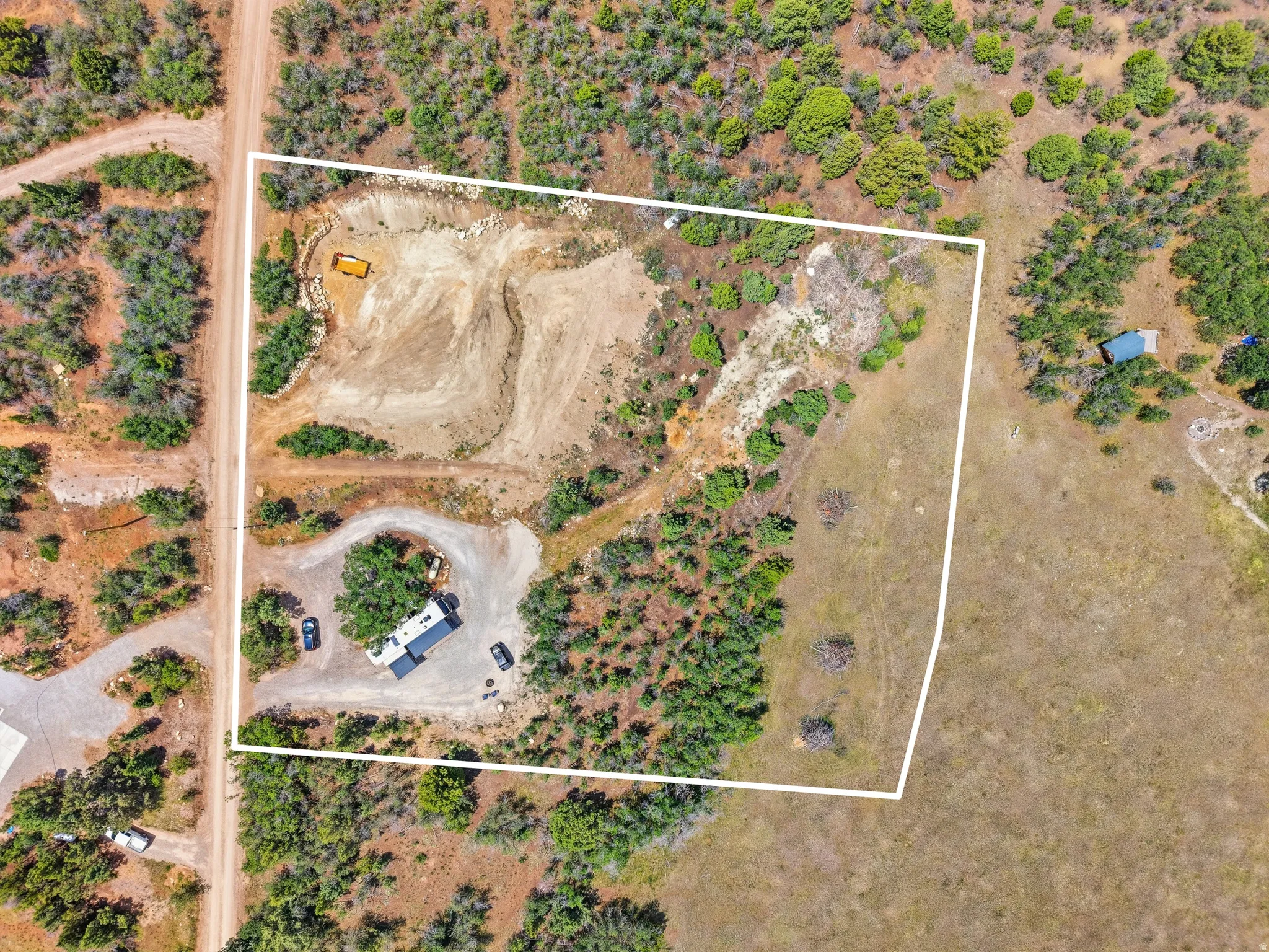 Expansive undeveloped parcel featuring a cleared building site, established driveways, natural tree coverage, and direct road frontage