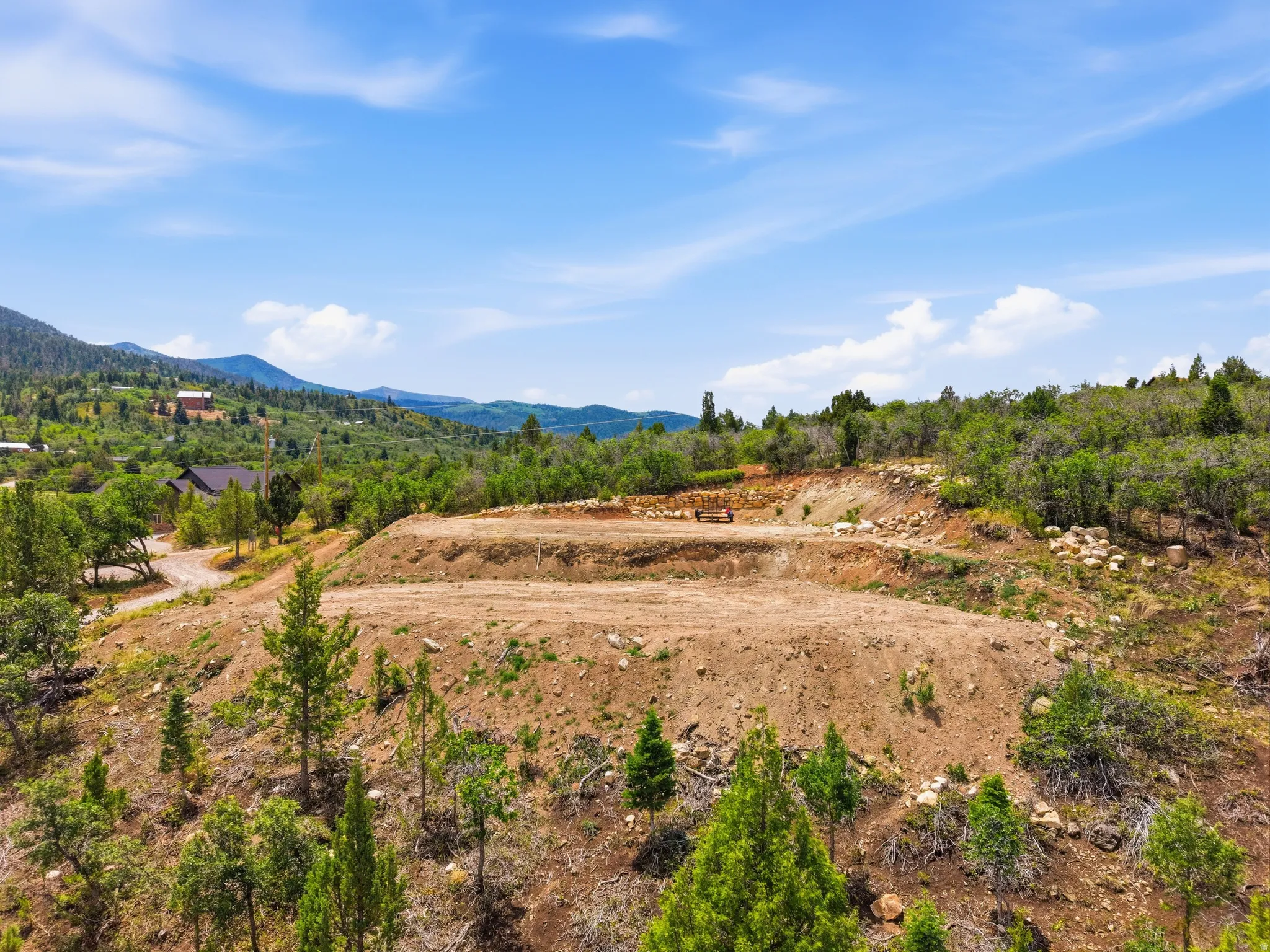 Graded building site featuring a level pad, sloped terrain, and surrounding natural foliage
