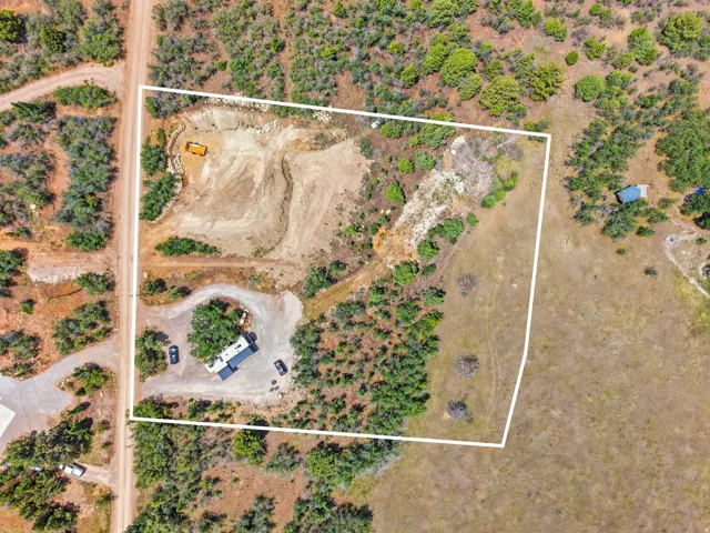 Expansive undeveloped parcel featuring a cleared building site, established driveways, natural tree coverage, and direct road frontage