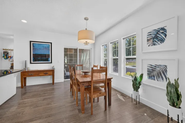 Dining area with wood-finish flooring, a contemporary drum pendant light, and three large windows