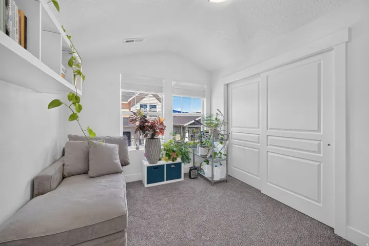 Bright room featuring a vaulted ceiling, two windows with white blinds, and a large sliding door with panel detailing