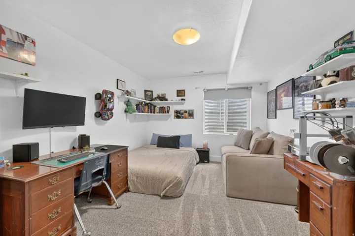Carpeted room featuring white walls, recessed window with blinds, and built-in shelving