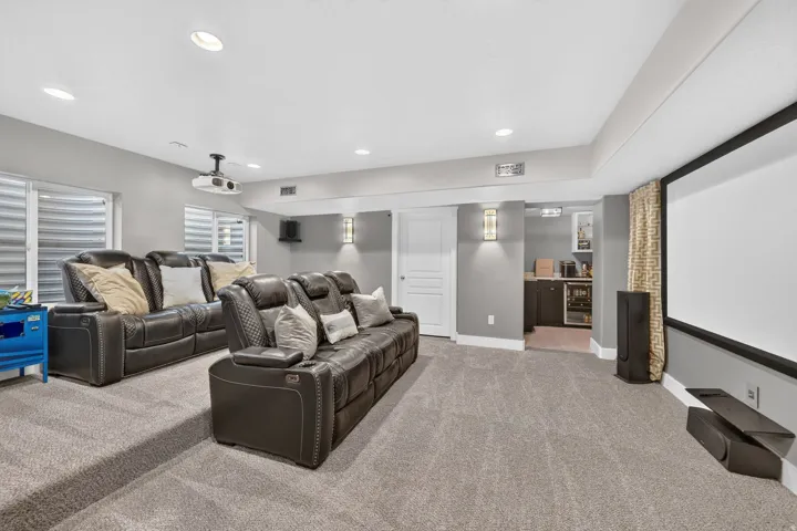 Spacious entertainment area featuring a large projection screen, recessed lighting, and soft gray carpeting