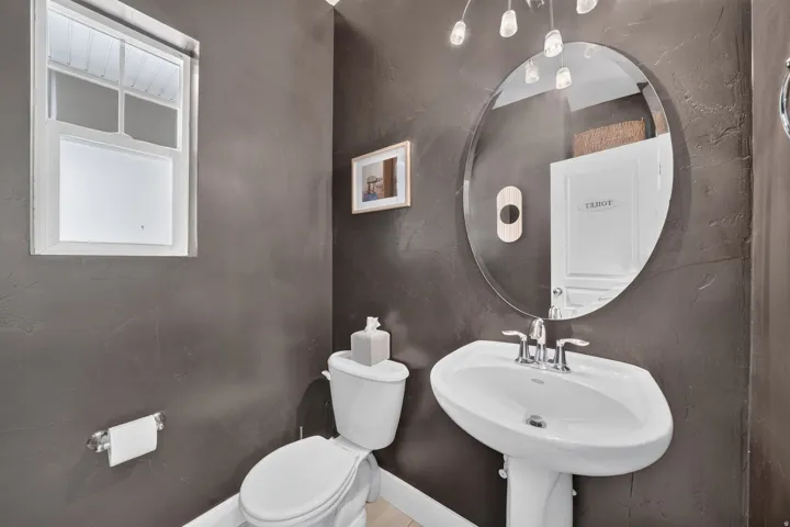 Pedestal sink with chrome fixtures and a large oval mirror