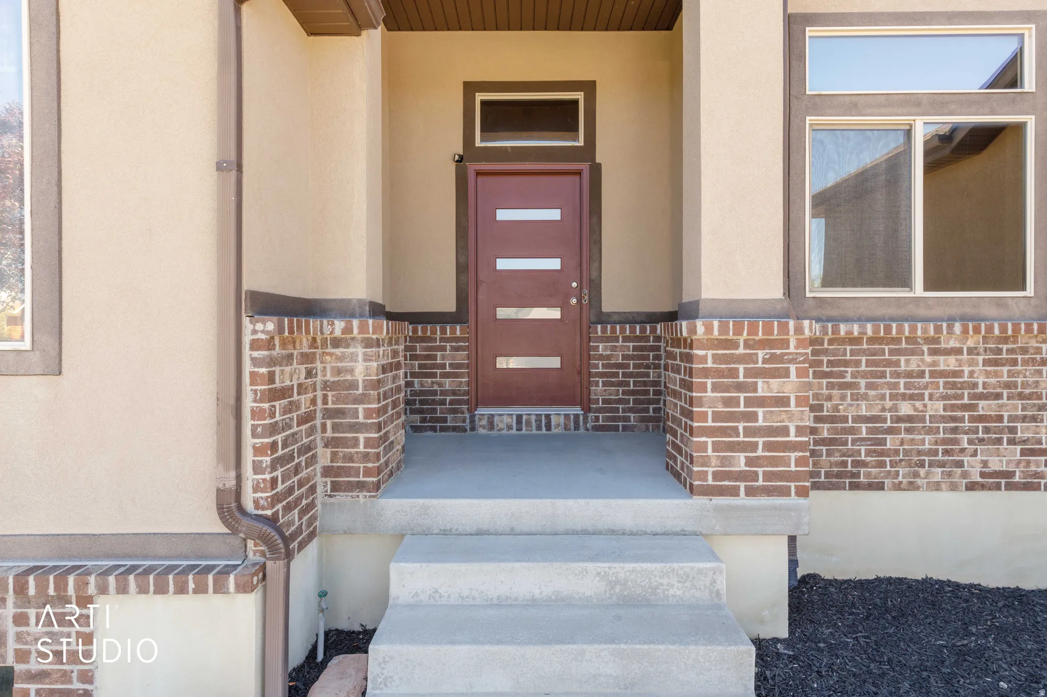 Contemporary front door with frosted glass inserts, a transom window, and a concrete stoop