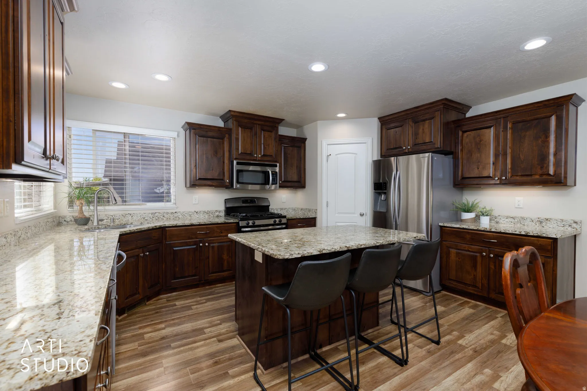 Kitchen with wood-finish flooring, dark wood cabinetry, and light-colored countertops