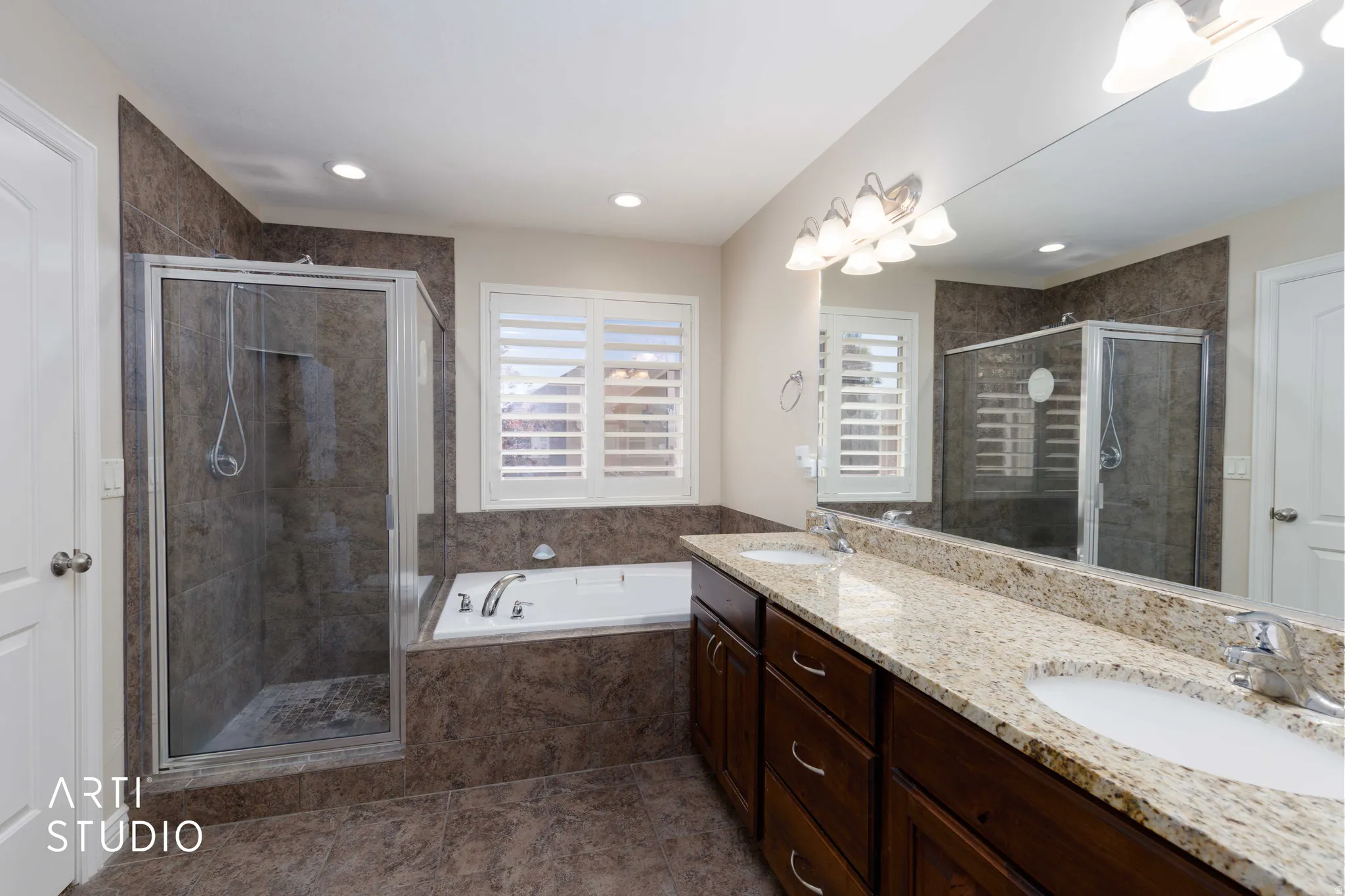 Bathroom featuring a spacious dual vanity with light granite countertops, dark wood cabinetry, and individual undermount sinks