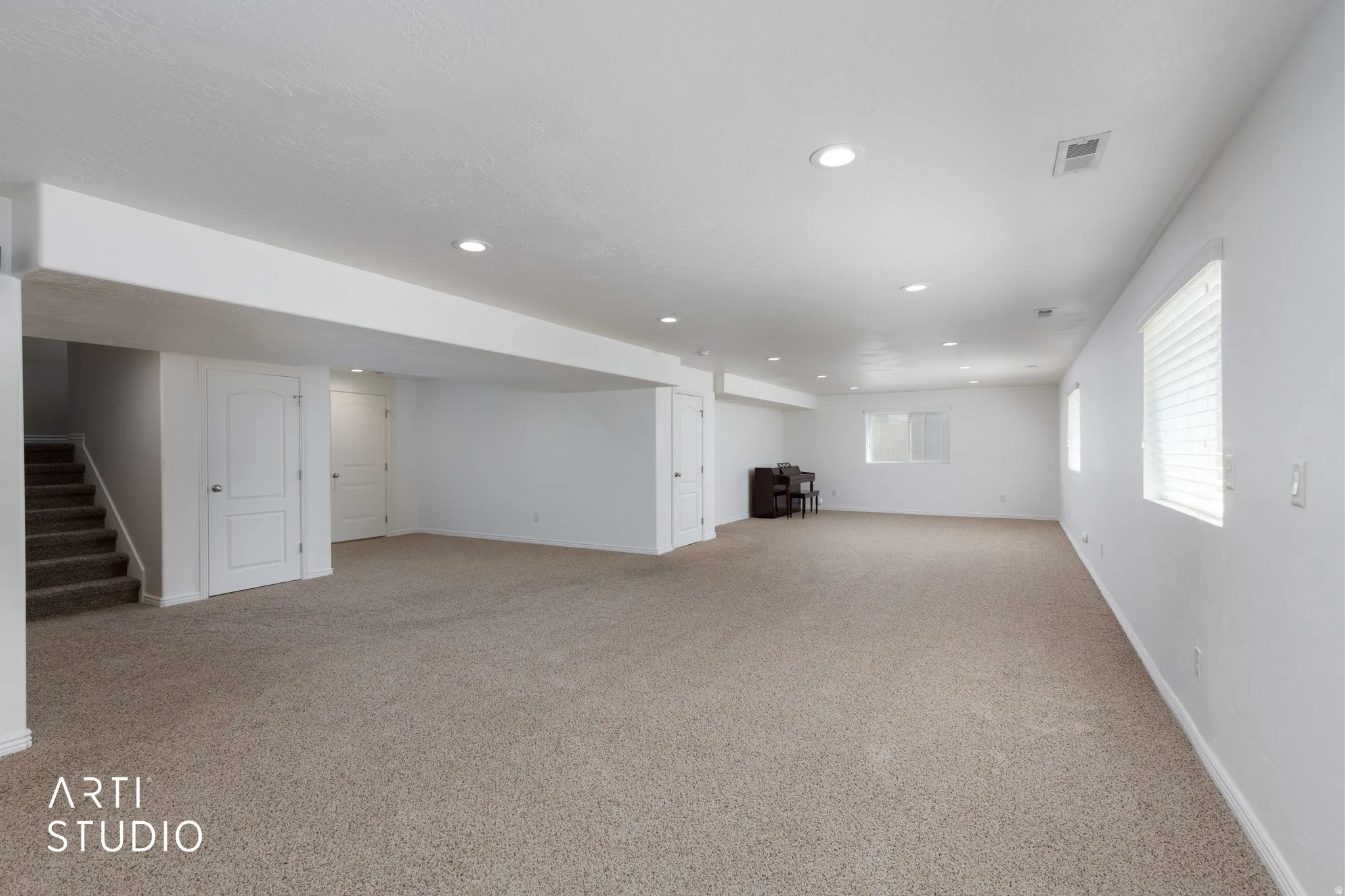 Expansive open-concept room featuring neutral carpet flooring, recessed lighting, and multiple windows with blinds