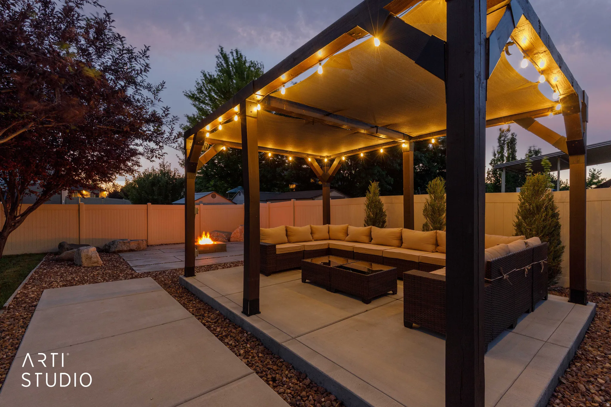 Outdoor living area featuring a pergola with integrated lighting, a concrete patio, and a dedicated fire pit