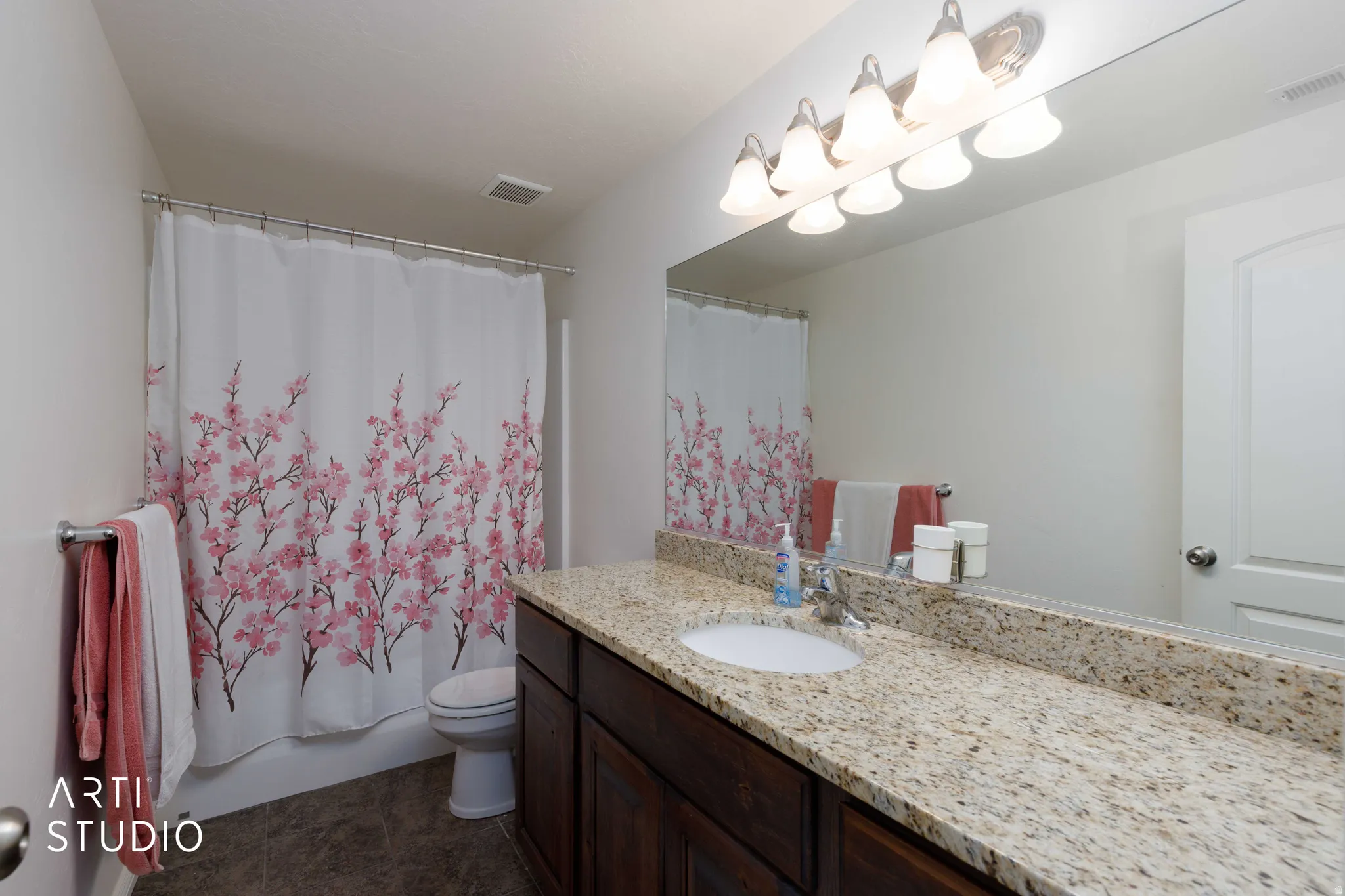 Bathroom featuring a vanity with a light-colored speckled countertop, an undermount sink, and dark wood cabinetry
