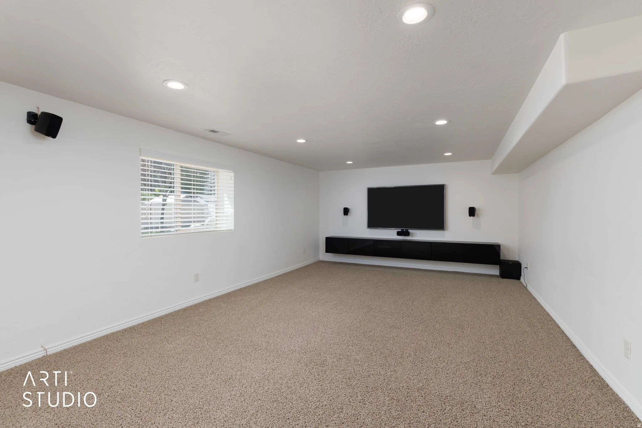 Spacious room featuring neutral carpet flooring, recessed lighting, and a window with blinds