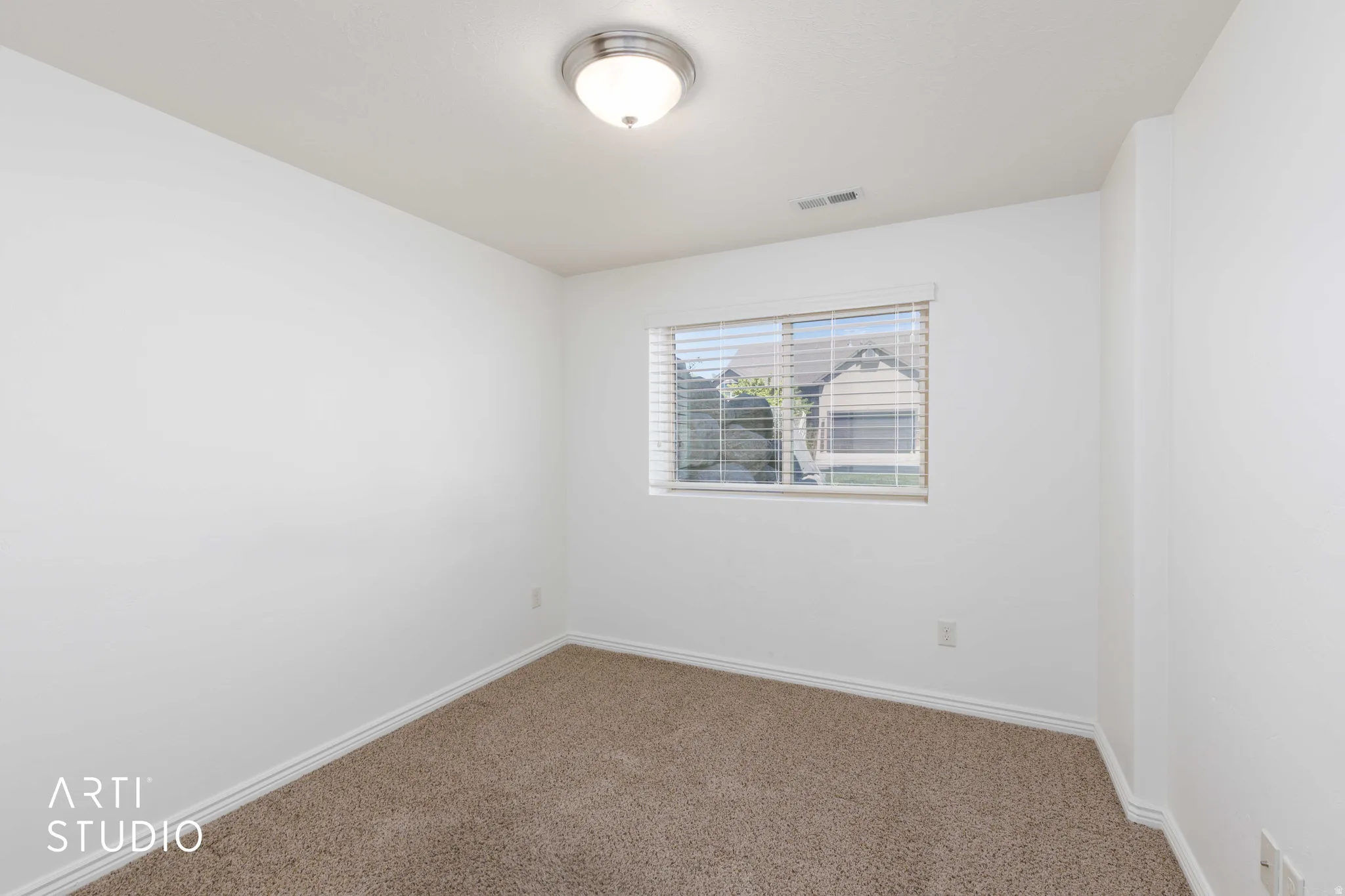 Carpeted room with white walls, a single window featuring blinds, and a flush-mount ceiling light fixture