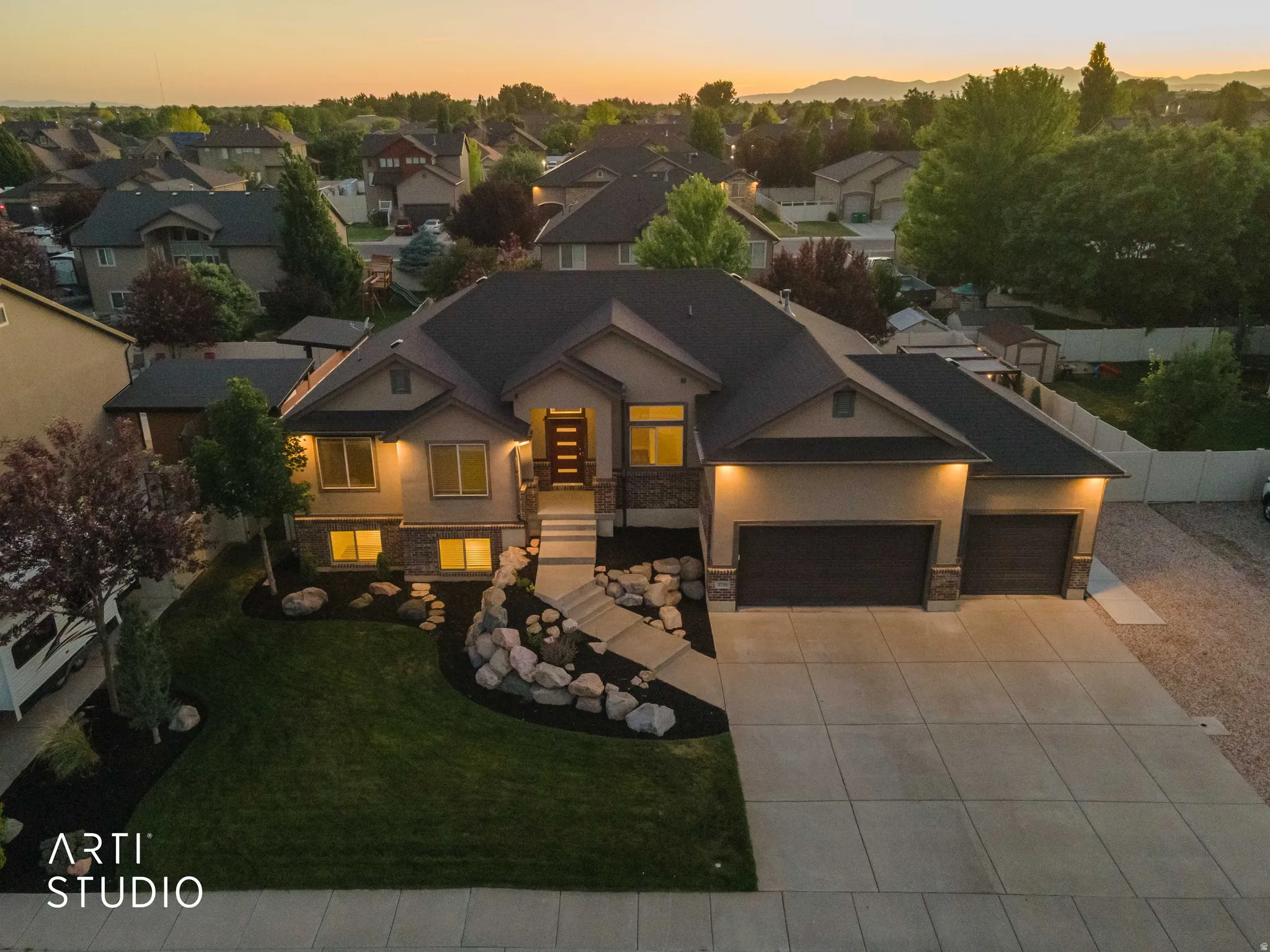 Modern residence featuring a stucco and stone facade, a two-car garage, and a concrete driveway
