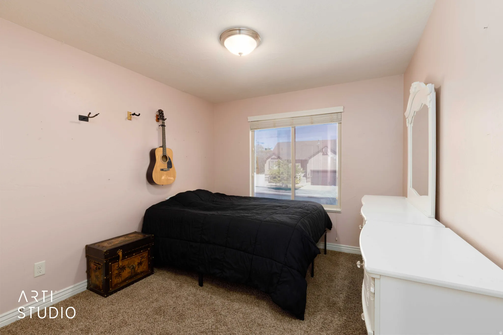 Bedroom featuring soft pink walls, a window with a white frame, and textured carpet flooring