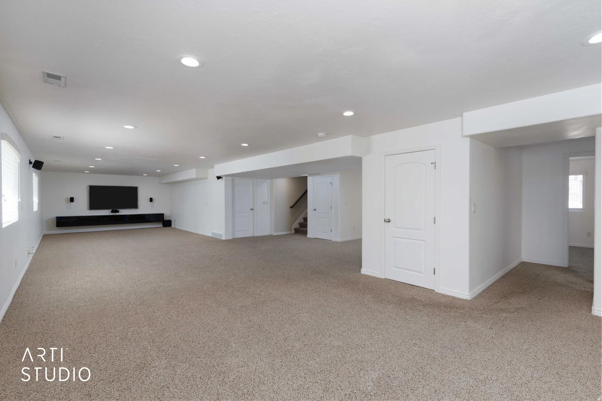 Spacious carpeted room featuring recessed lighting, a built-in media console, multiple windows with blinds, and white interior doors