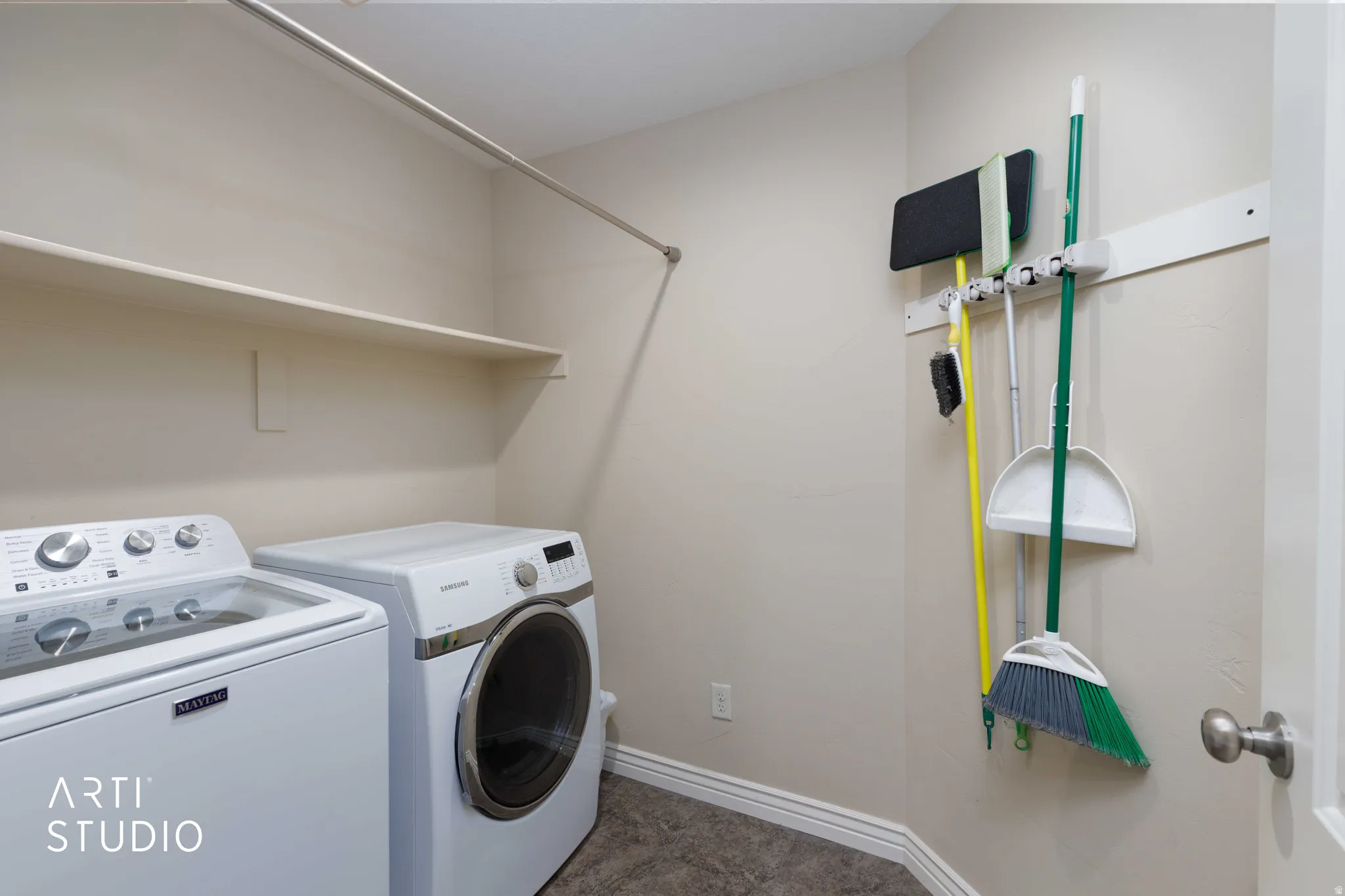Dedicated laundry area featuring a shelf, hanging rod, and textured flooring