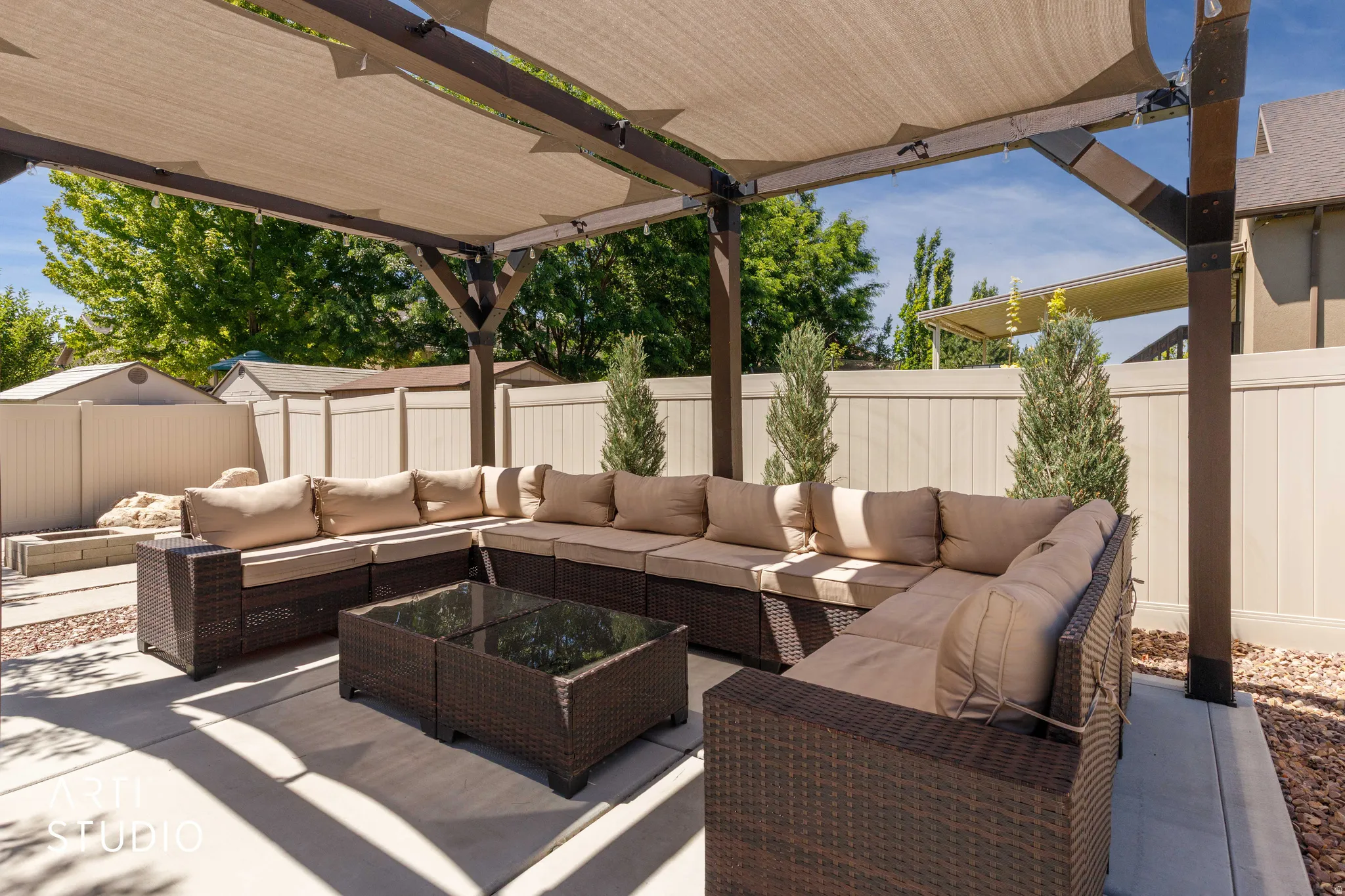 Patio featuring a pergola with retractable fabric shade, concrete flooring, and surrounding privacy fencing