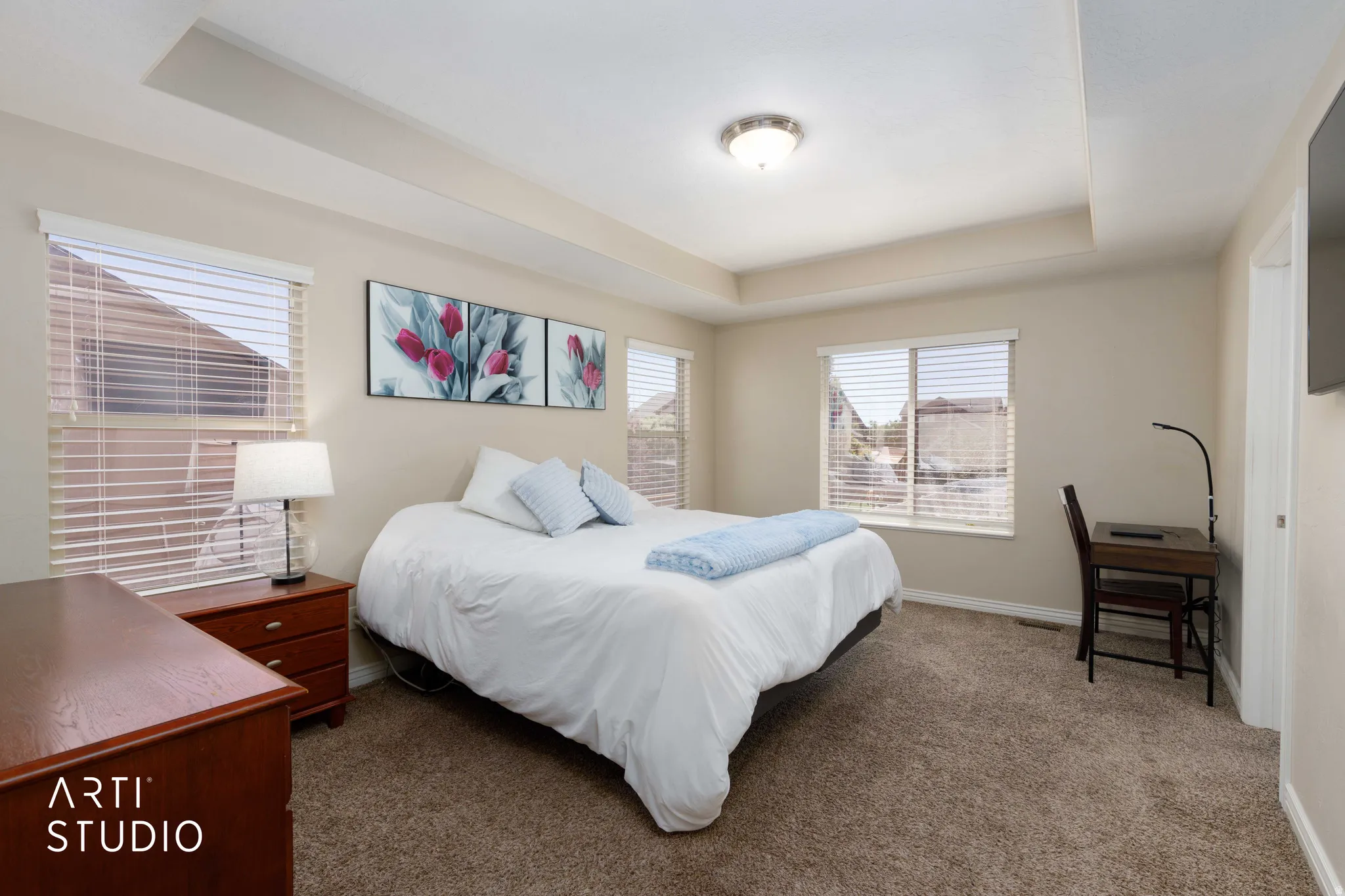 Spacious room featuring tray ceiling, recessed lighting, neutral-toned walls, multiple windows with blinds, and plush carpeting