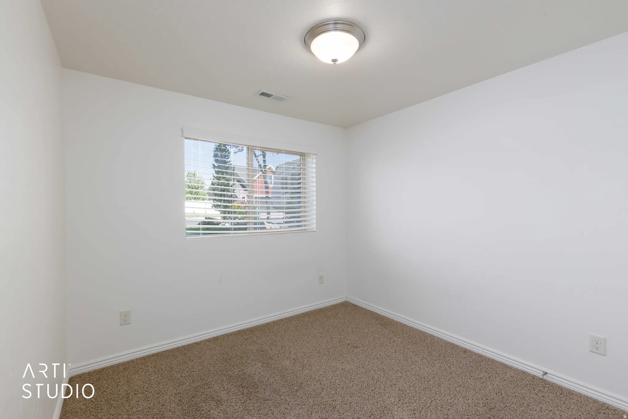 Carpeted room with a rectangular window featuring horizontal blinds