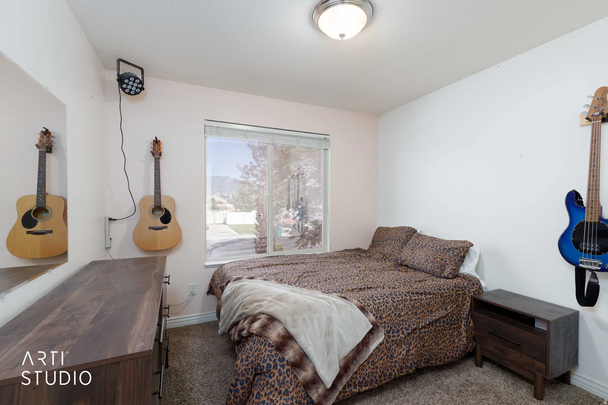 Bedroom featuring a single window with blinds, a ceiling-mounted light fixture, and neutral-toned walls