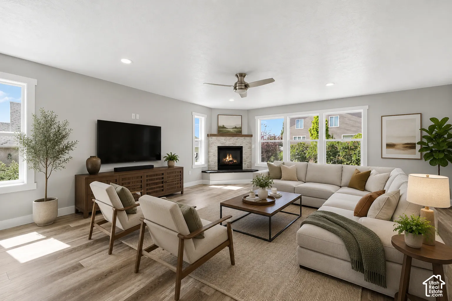 Spacious living area featuring plank wood-finish flooring and a corner stone-faced fireplace with a natural wood mantle