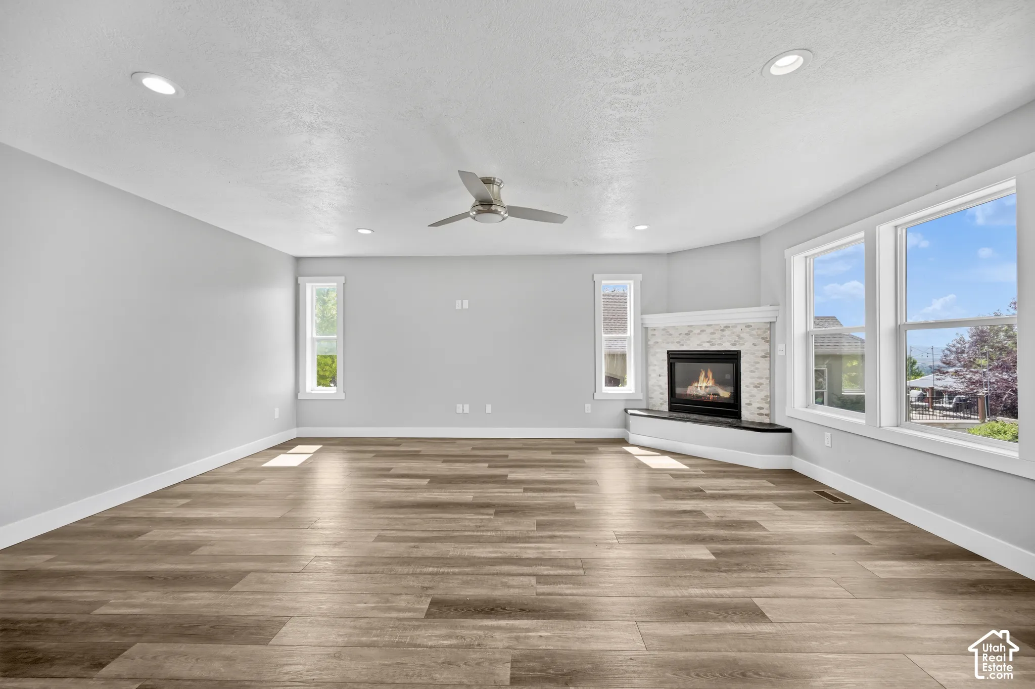 Spacious room featuring wood-finish flooring, recessed lighting, and a contemporary ceiling fan