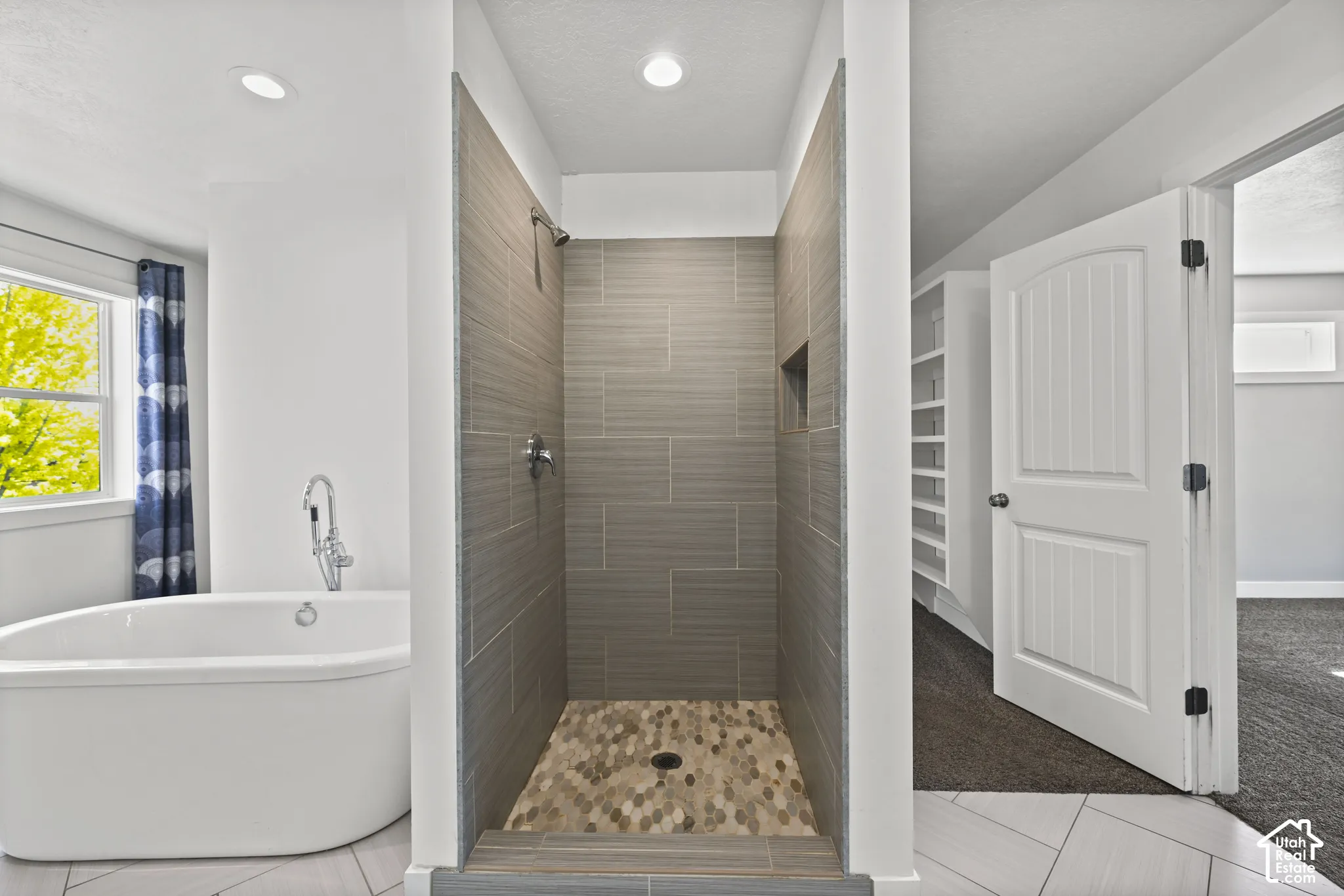 Contemporary bathroom featuring a freestanding soaking tub with a floor-mounted faucet, a walk-in shower with horizontal tile walls, a built-in shower niche, and a mosaic tile shower floor