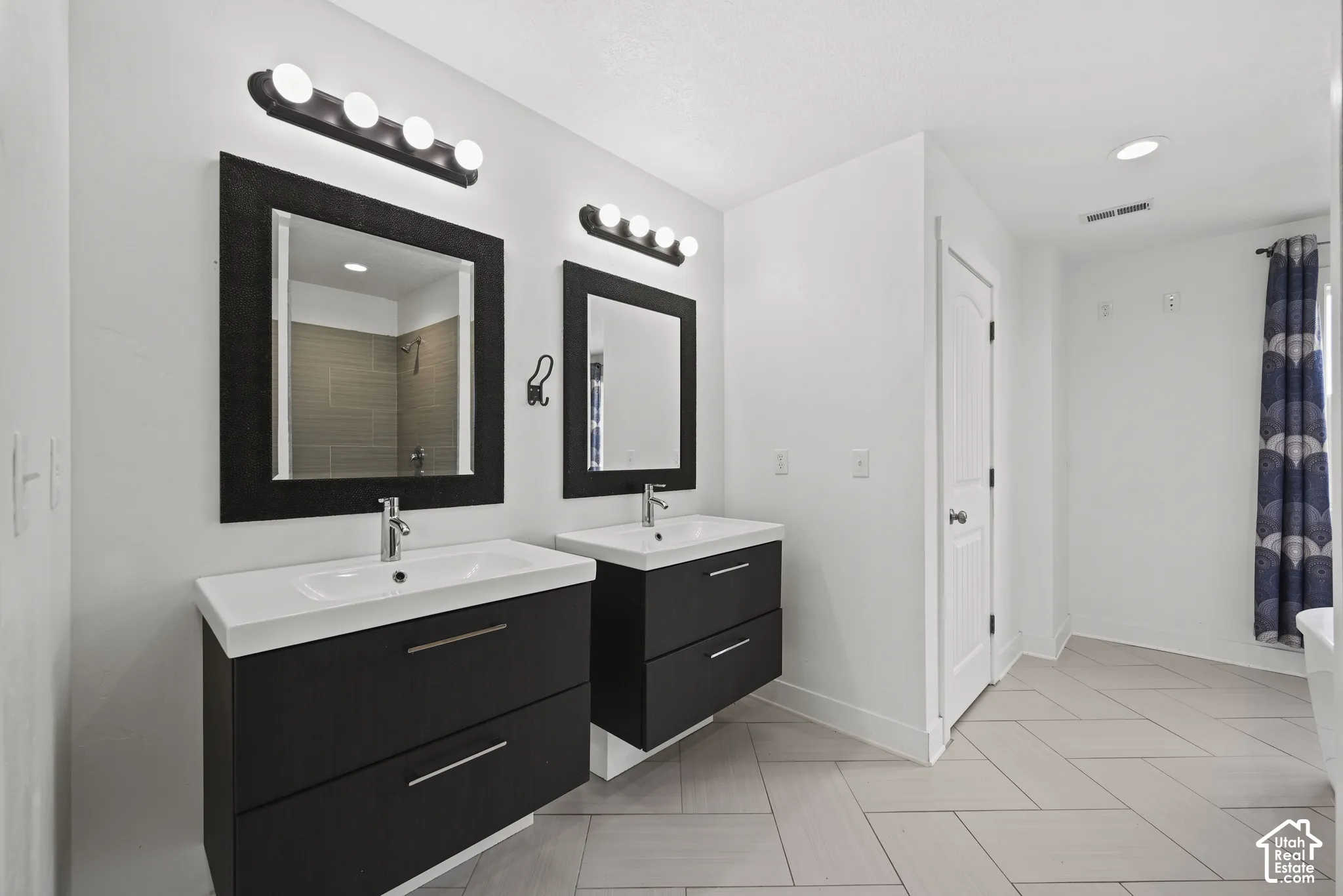 Dual floating vanities with integrated sinks, contemporary wall-mounted light fixtures, and coordinating framed mirrors