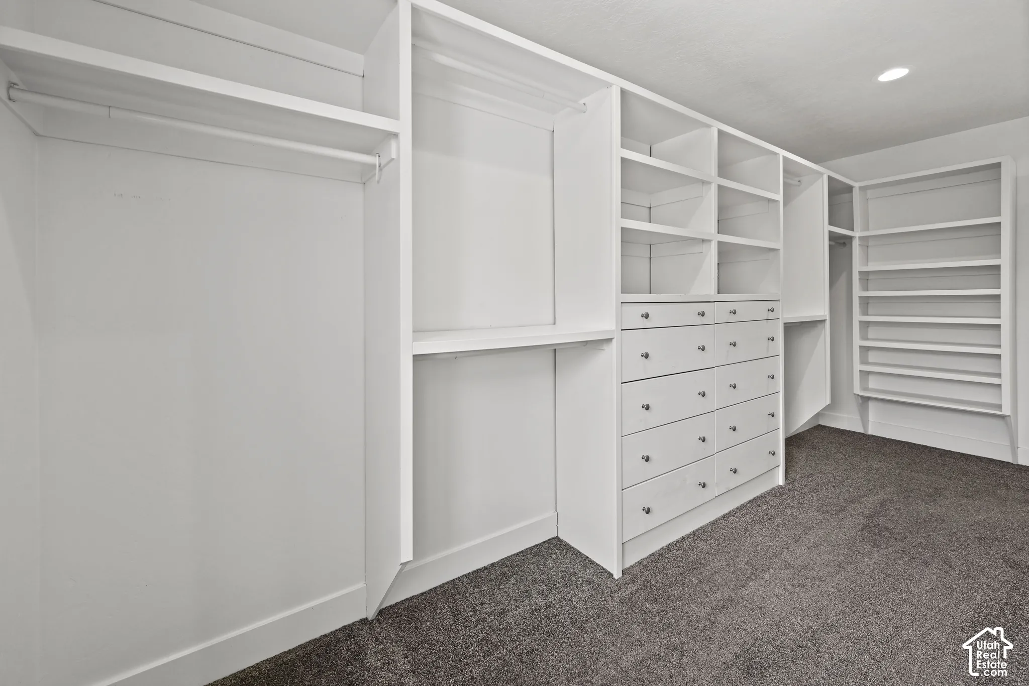 Custom closet system featuring white built-in shelving, hanging rods, and integrated drawer units with silver hardware