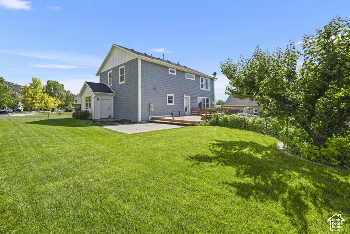 Expansive backyard featuring a lush lawn, a concrete patio, and a wood deck