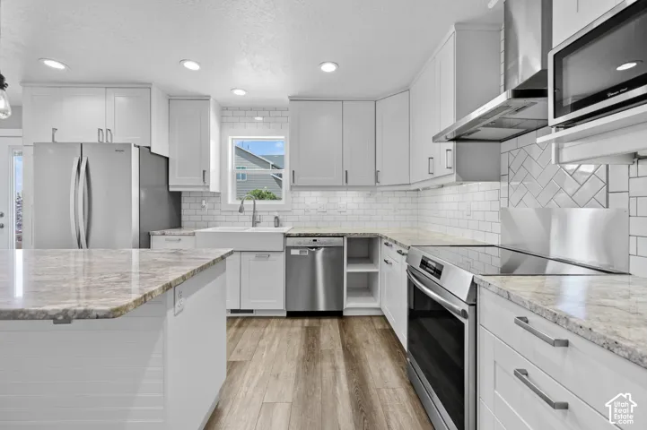 Contemporary kitchen featuring white cabinetry, stainless steel appliances, granite countertops, wood-finish flooring, and a subway tile backsplash