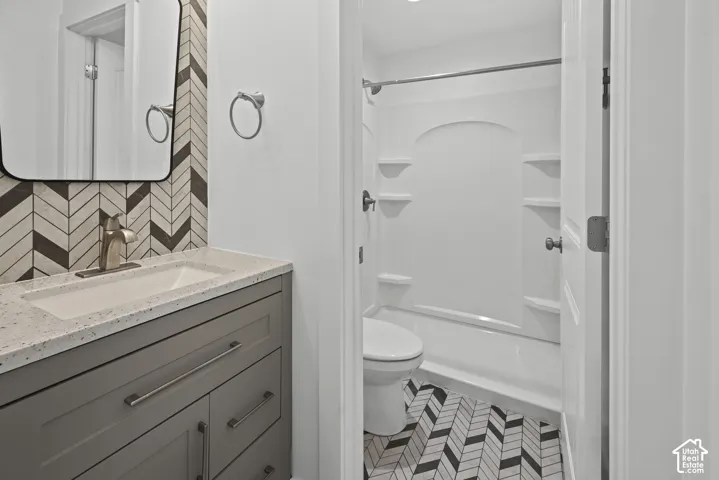 Bathroom featuring a vanity with a light-toned countertop, an integrated sink, and gray cabinetry with brushed nickel hardware