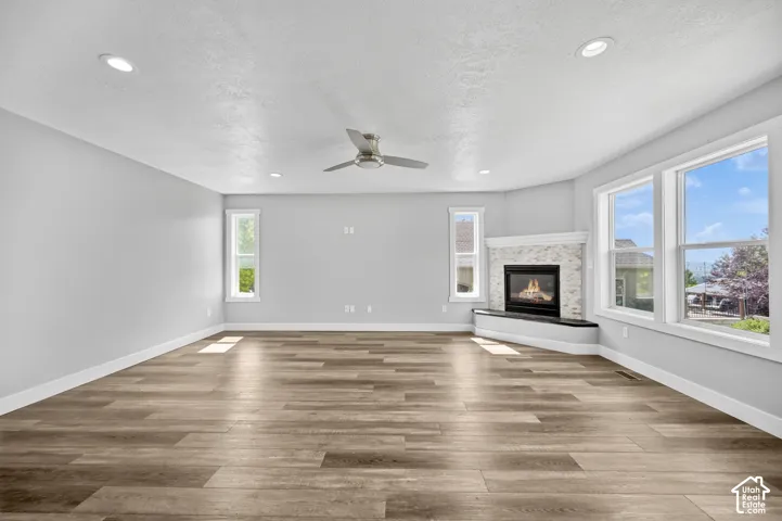 Spacious room featuring wood-finish flooring, recessed lighting, and a contemporary ceiling fan