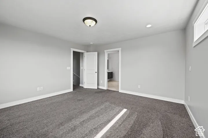 Spacious carpeted room featuring light gray walls, white trim, and a ceiling light fixture