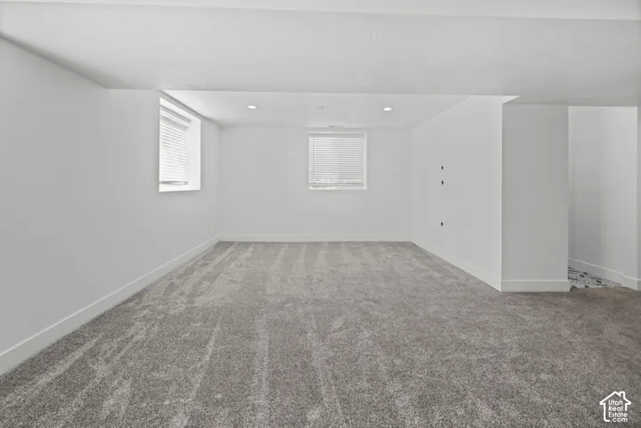 Spacious room featuring neutral carpeting, white walls, and two windows with blinds