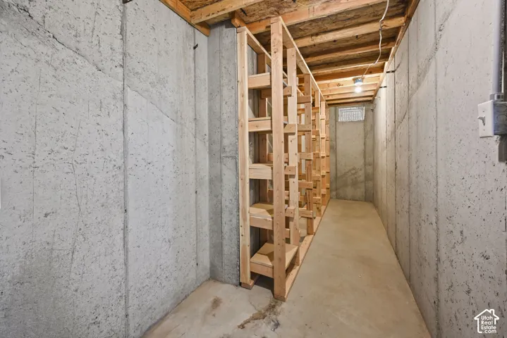 Basement area featuring concrete walls, concrete flooring, and exposed wood ceiling joists