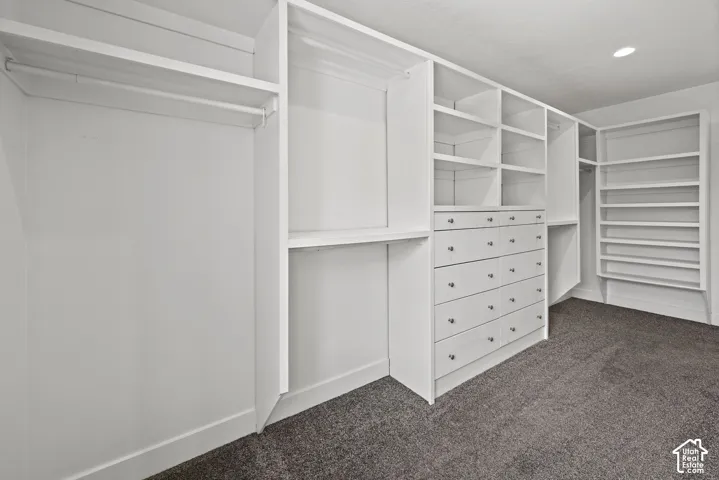 Custom closet system featuring white built-in shelving, hanging rods, and integrated drawer units with silver hardware