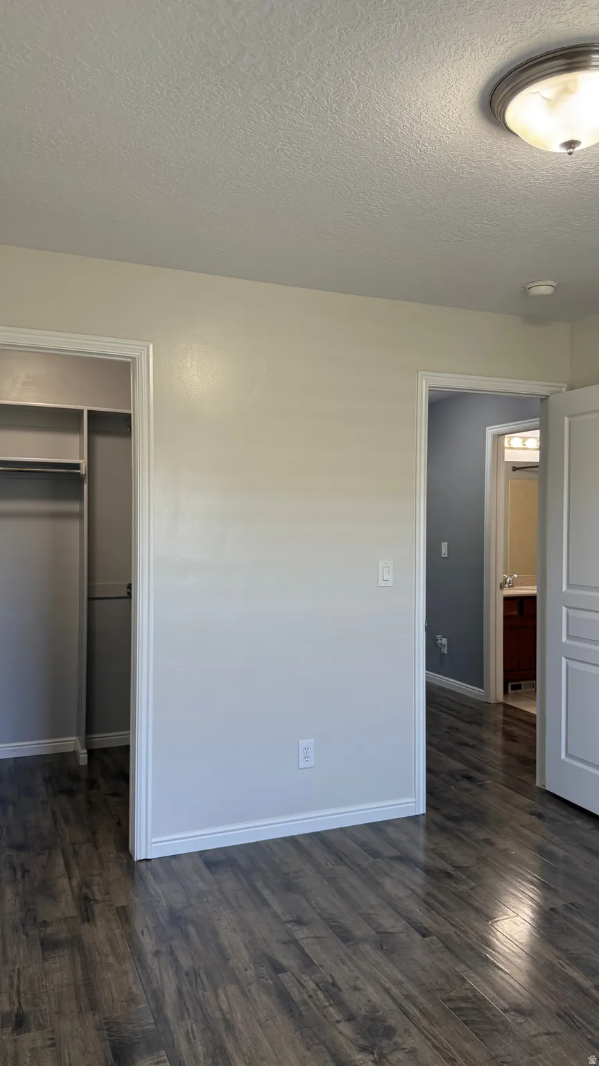 Interior room featuring wood-finish flooring, light-toned walls, a built-in closet with shelving, and a flush-mount ceiling light fixture