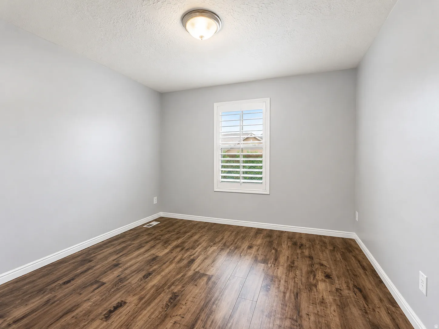 Room featuring wood-finish flooring, light grey painted walls, and white baseboards
